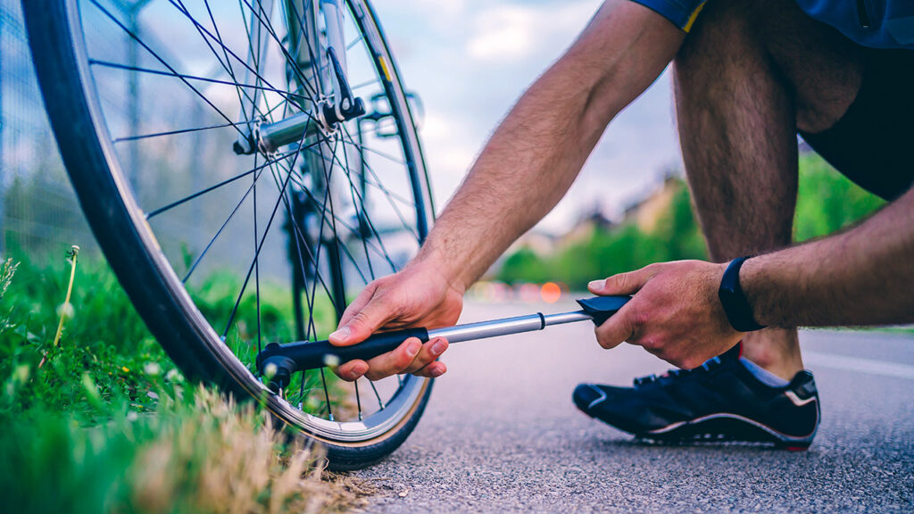 Male cyclist pumping up a flat bicycle tire